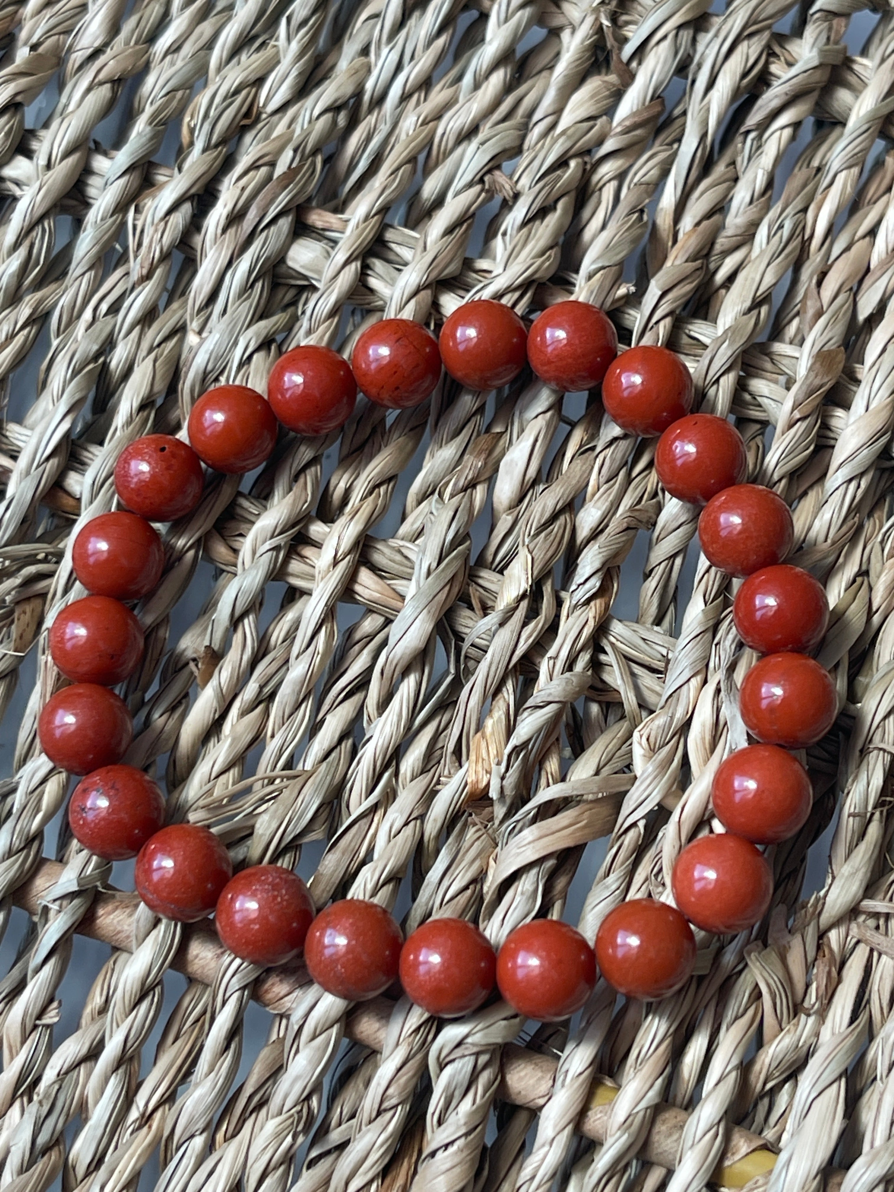 Red beaded bracelet on a woven surface