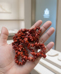 Red stone necklace on a hand with a blurred background