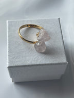 Rose quartz gold ring with pink crystals on a textured white jewelry box