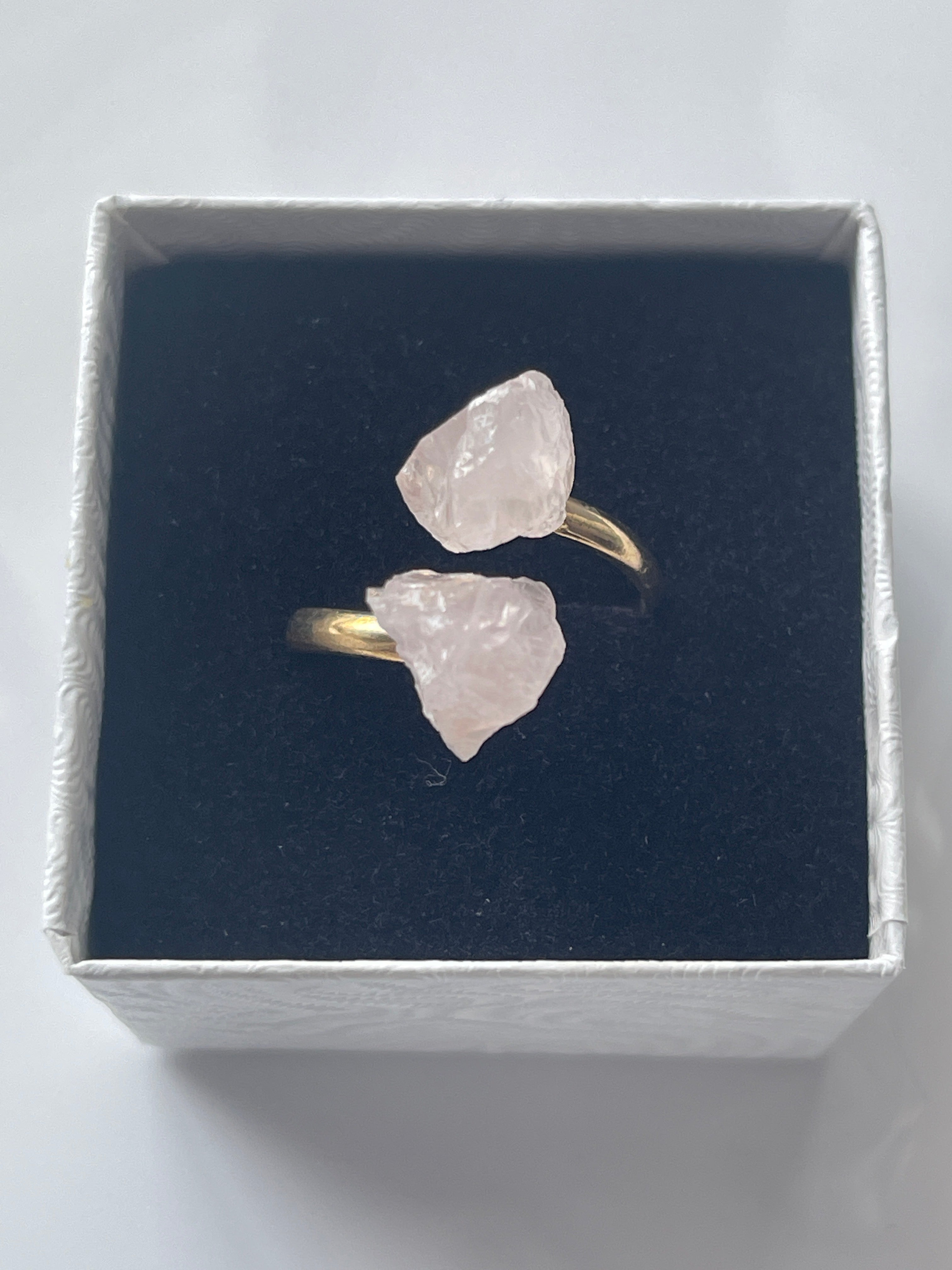 Rose quartz raw gold pink crystal ring in a jewelry box on a light white background