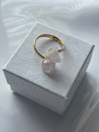 Rose quartz gold ring with a pink crystal on a textured white jewelry box