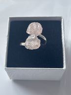 Rose quartz silver ring with rough stones on a black cushion in a white jewelry box.
