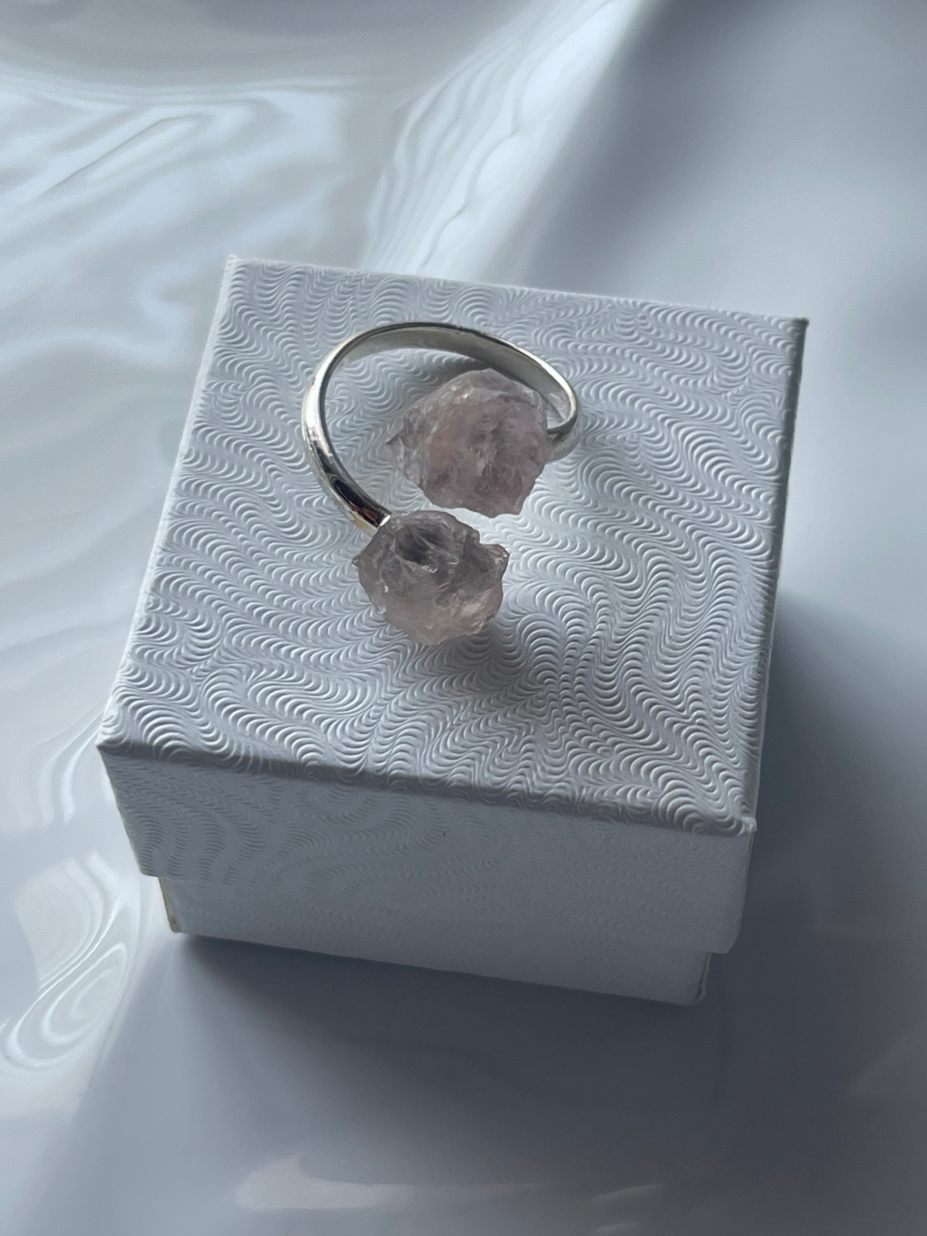 Rose quartz sliver ring on a textured white jewelry box 