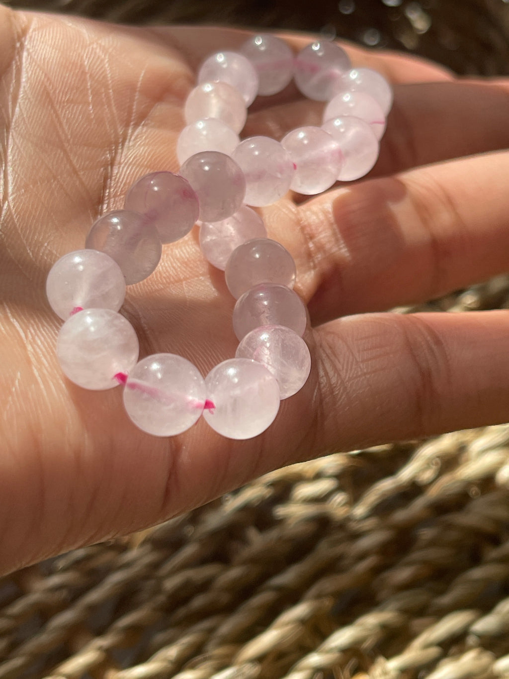 Hand holding a pink quartz bracelet with pink beads against a blurred background