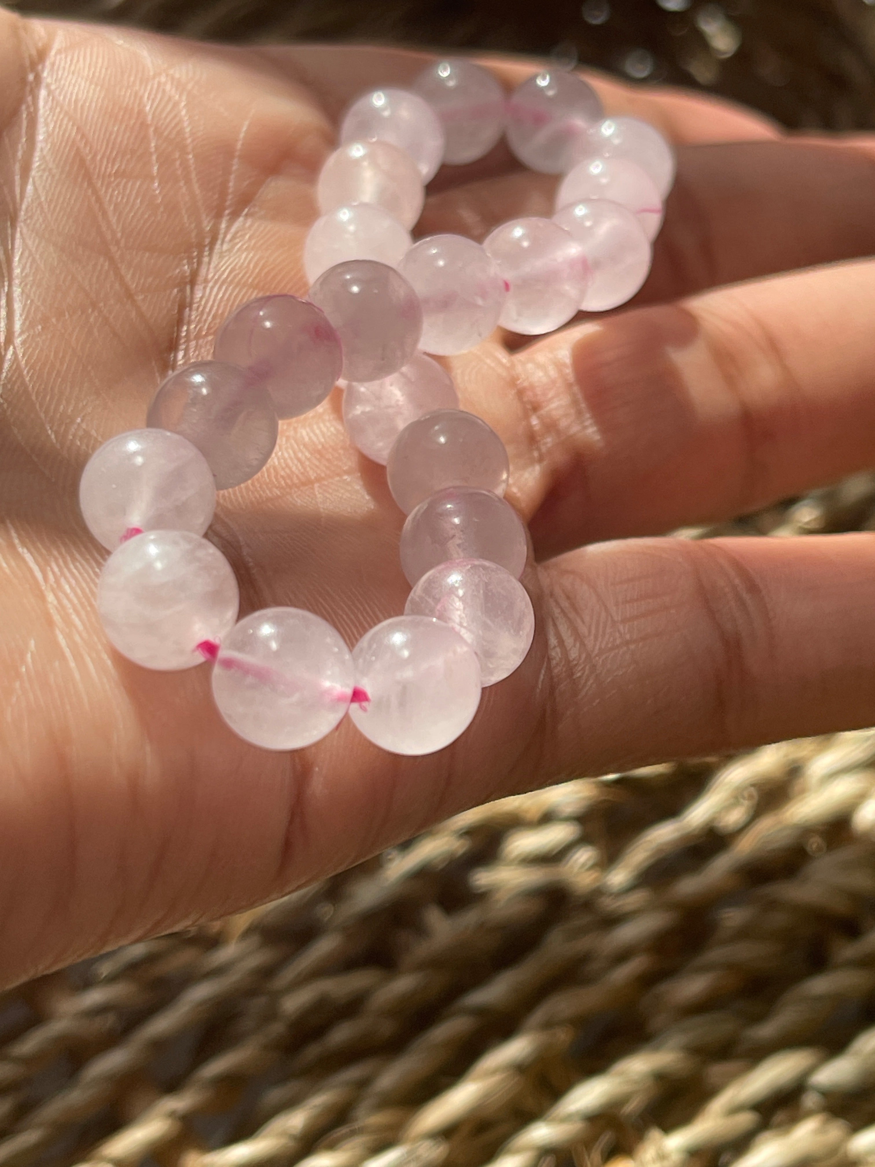 Hand holding a pink quartz bracelet with pink beads against a blurred background