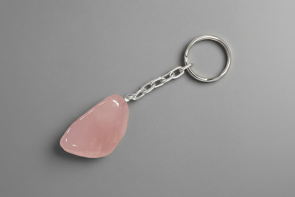 A polished Rose Quartz keychain against a gray background.