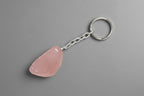 A polished Rose Quartz keychain against a gray background.