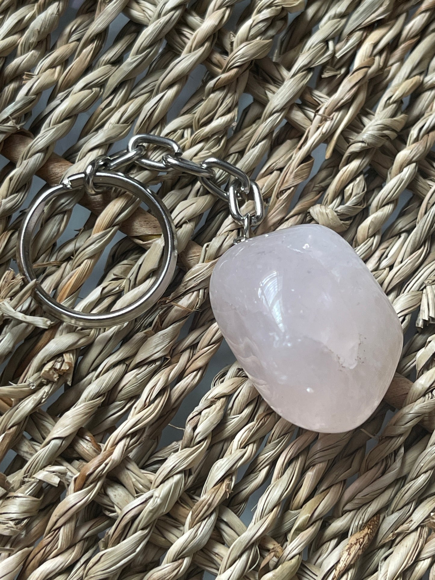 Rose quartz Keychain with a pink stone on a woven surface