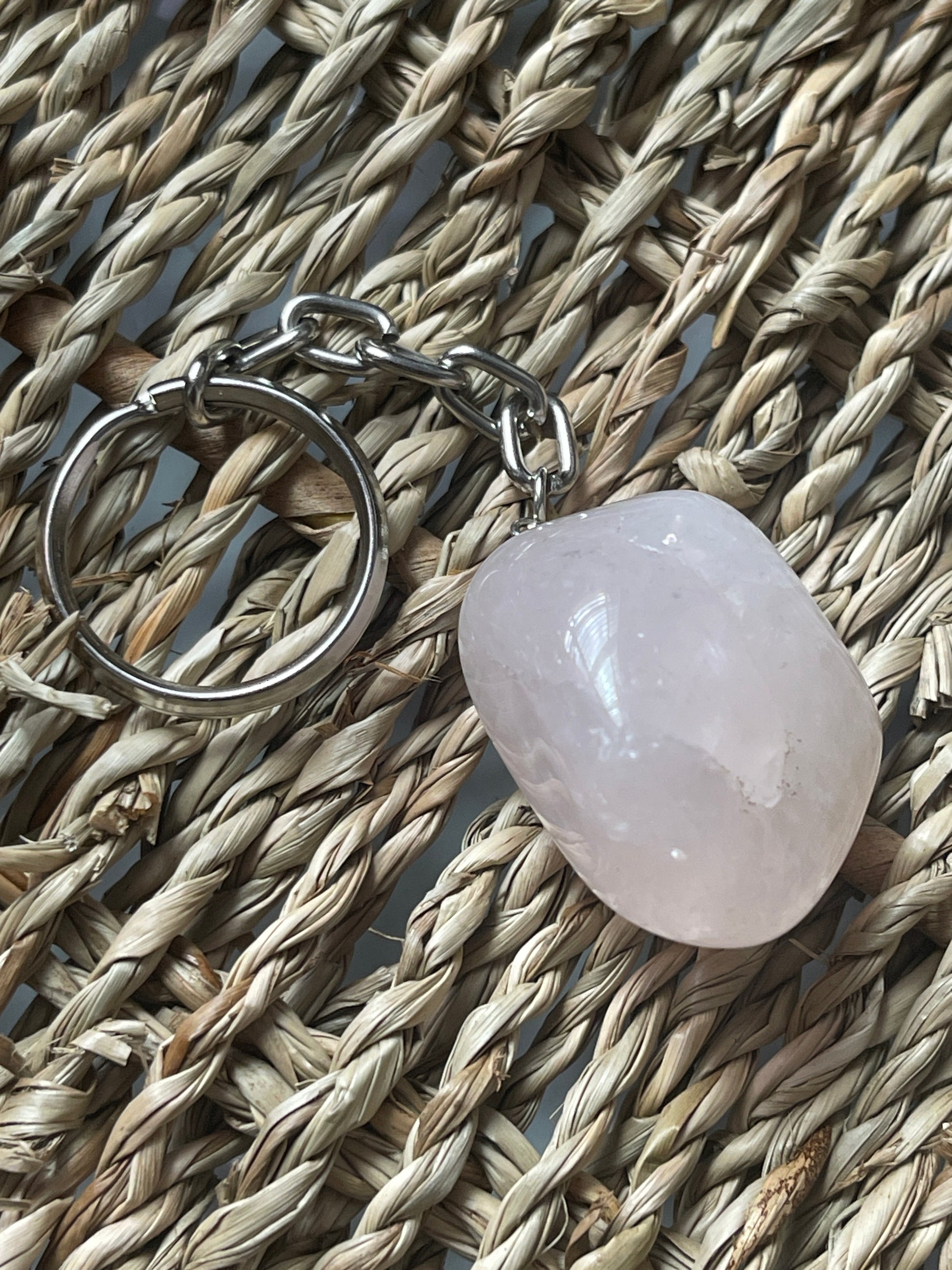 Rose quartz Keychain with a pink stone on a woven surface