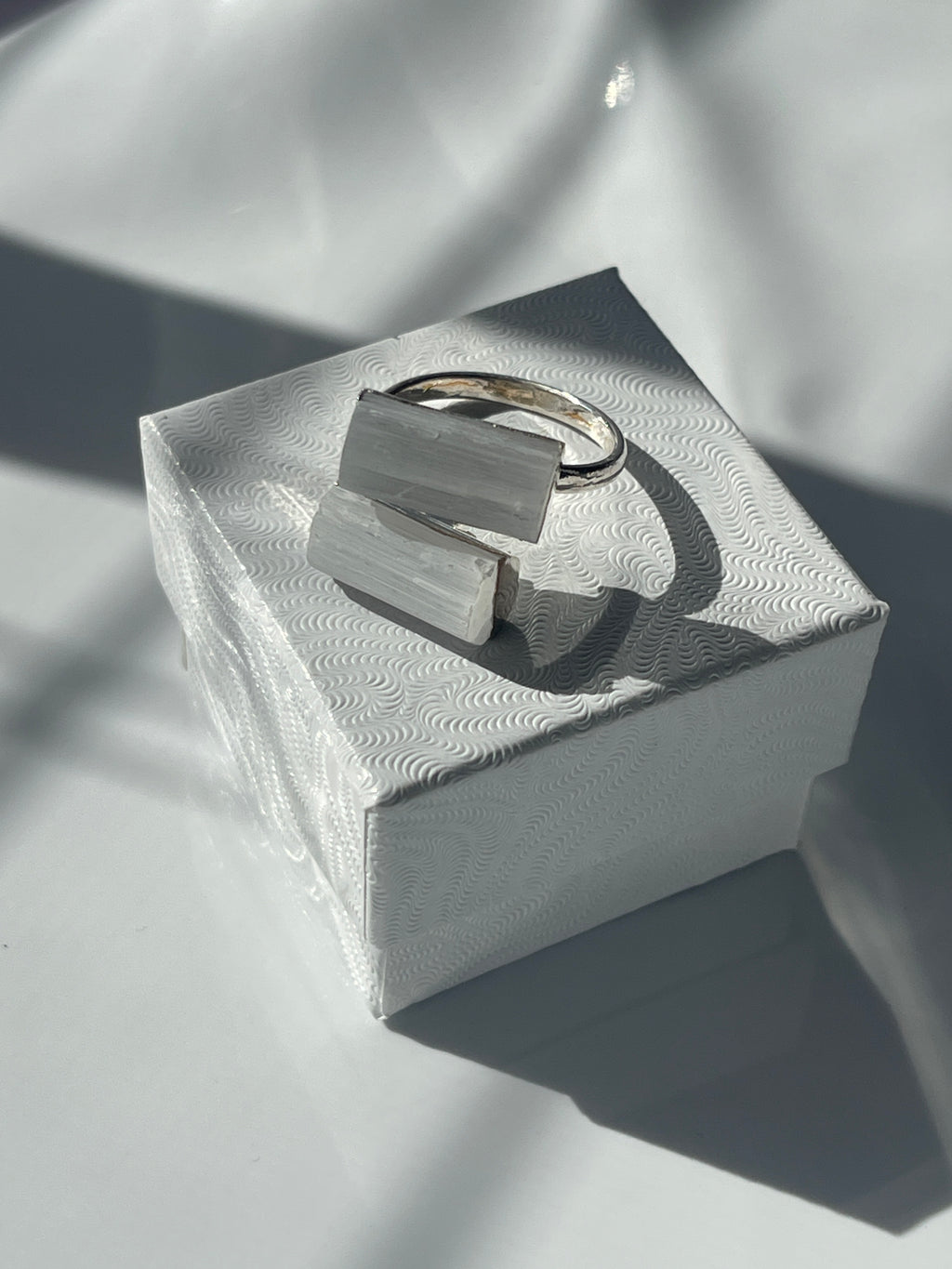 Selenite silver plated ring with a geometric white stone on a textured white jewelry box in Florida 