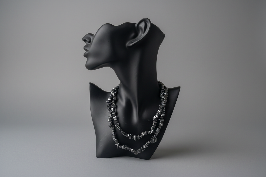 Black stone necklace on a black mannequin bust against a gray background