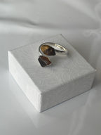 Tigers eye sliver plated ring, brown stone on a textured white jewelry box top against a white background
