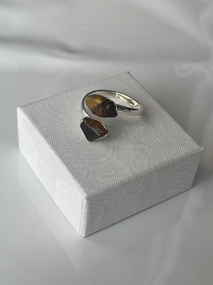 Tigers eye sliver plated ring, brown stone on a textured white jewelry box top against a white background