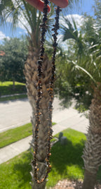 Tigers_Eye_Chip_Necklace_30-32_Inches with black beads held up to palm trees