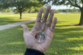 Hand holding a colorful tree of life keychain with a blurred natural park background
